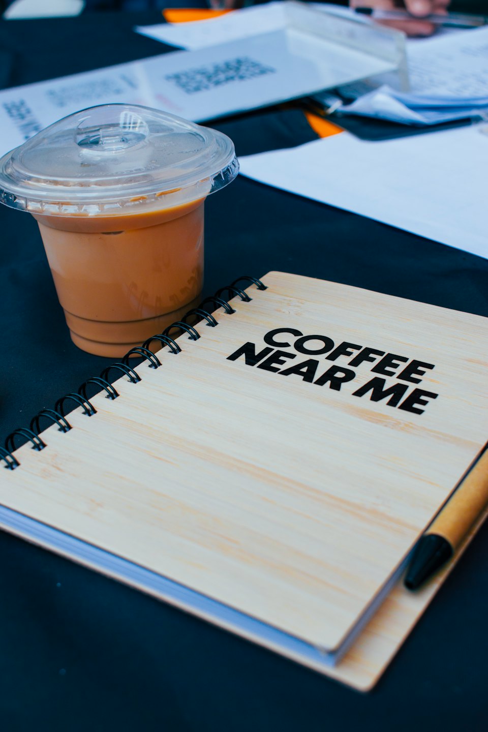 Iced coffee and a wooden notebook on a table.